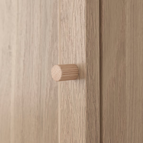 A close-up of a wooden cabinet door with a cylindrical knocker, showcasing the smooth grain and finish quality.