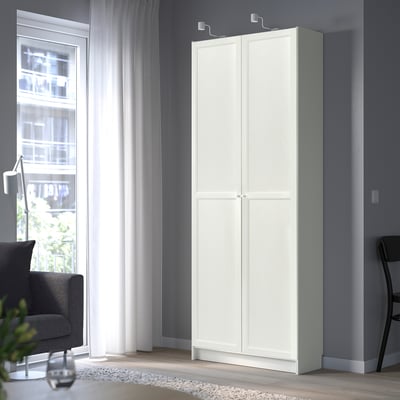 White BILLY bookcase in living room, two-door, beside window.