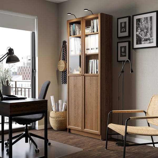 Home office with BILLY bookcase, wooden, tall, glass doors, desk, chair, window, city view.