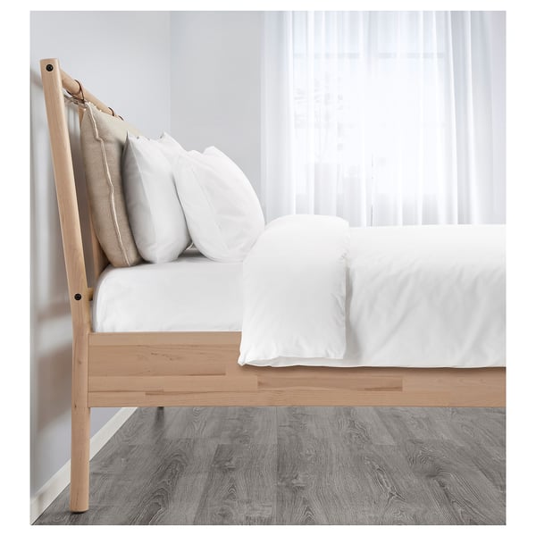 Bed frame with natural birch, white linens, and pillows. Adjustable bed sides and under-bed storage.