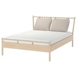 BJÖRKSNÄS bed with light wood frame and beige pillows.