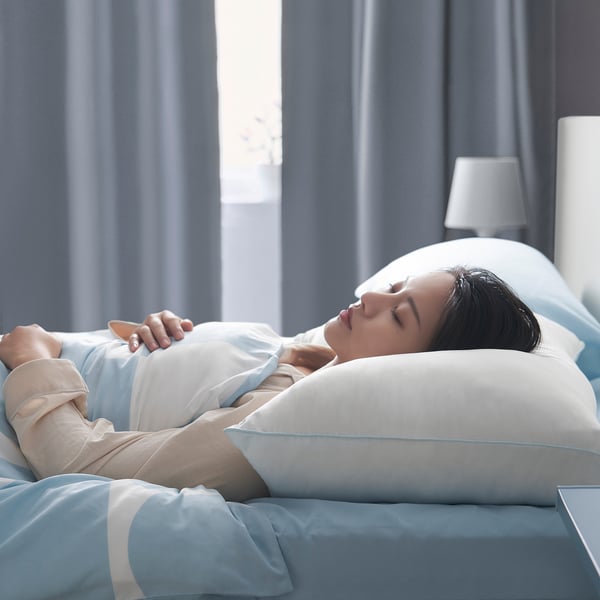 A person sleeps peacefully on a soft, white pillow with a brushed microfiber surface and airy filling, designed for side or back sleepers.