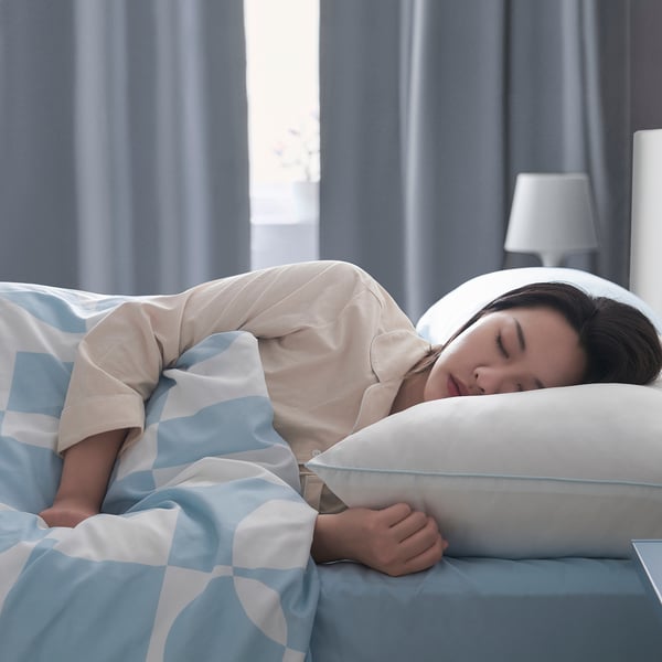 Person sleeps on hygienic, comfy pillow for side/back sleep.