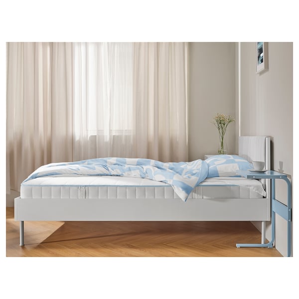 Neutral bedroom with white BRUKSVARA bed, light blue accents, wooden floor, sheer curtains.