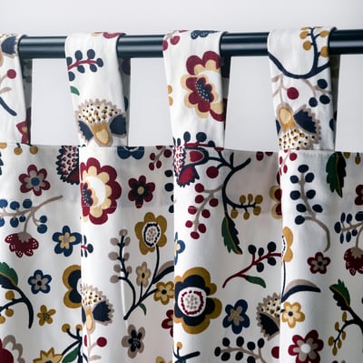 Curtained window with floral pattern; tab headings for direct curtain rod hanging.