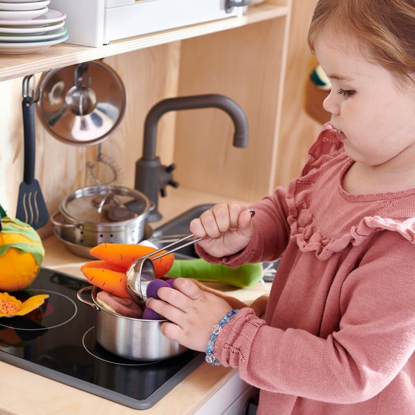 Girl plays with toy kitchen tools.