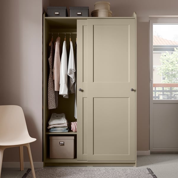 Beige HAUGA wardrobe with sliding doors, both hanging and shelves, in a room with a white chair.