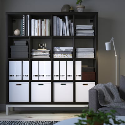 KALLAX shelving with books & boxes next to an armchair.
