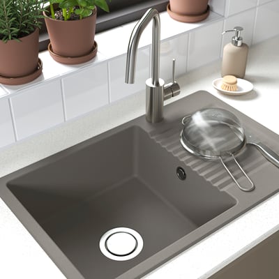 Dark grey composite sink with modern tap, strainer, and potted plants.