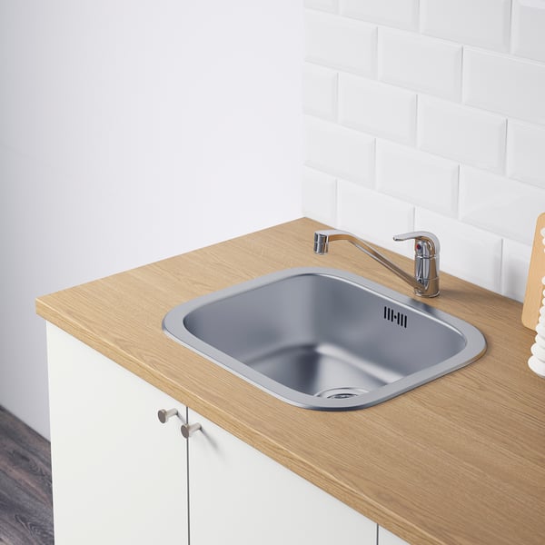 Modern kitchen sink with chrome tap and drain on wooden counter.