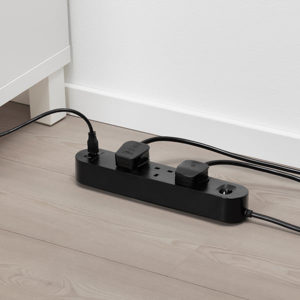 Black multi-socket adapter with usb ports on wooden floor. It powers and charges multiple devices simultaneously.