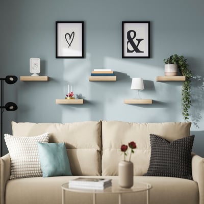 Modern living room with blue walls, LACK shelves, art, plants, beige sofa, coffee table.