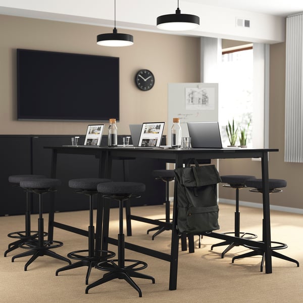 Modern office setup with MITTZON high table, stools, laptop, and large tv for meetings.