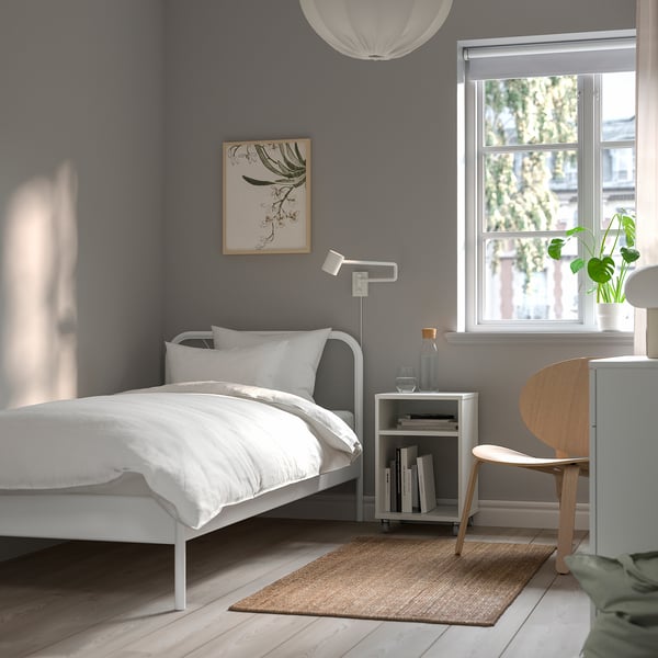 Modern grey bedroom with NESTTUN bed, pendant lamp, side table, and chair. Beige rug on light wood floor.