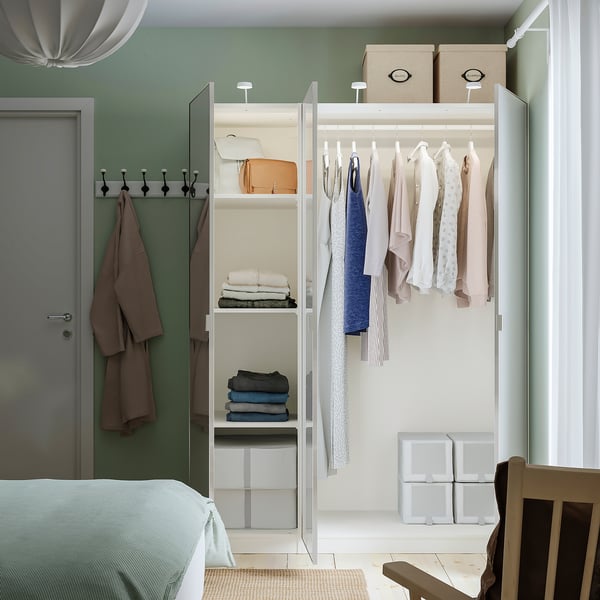 Modern closet with clothes, shelves, and towels. Mirrored doors expand space, reflecting light. Efficient wardrobe solution.