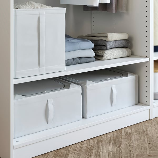 White PAX storage unit with folded clothes and fabric bins on shelves.