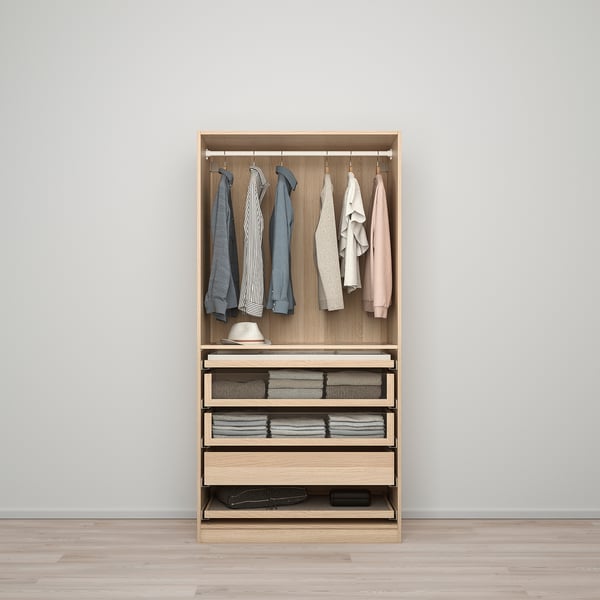 A modern wooden PAX wardrobe organises clothes neatly. It hanging garments, folded clothes in drawers, and shelf storage.