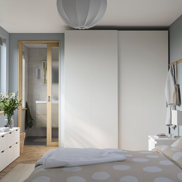 Modern bedroom with large PAX wardrobe, polka dot bed, and glass-door bathroom.