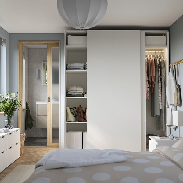 Bedroom with PAX wardrobes: open for clothes, closed with sliding doors, grey walls, wooden floor.