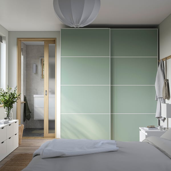 Modern bedroom with large green glass PAX wardrobe. Beside en-suite bathroom with wood accents.