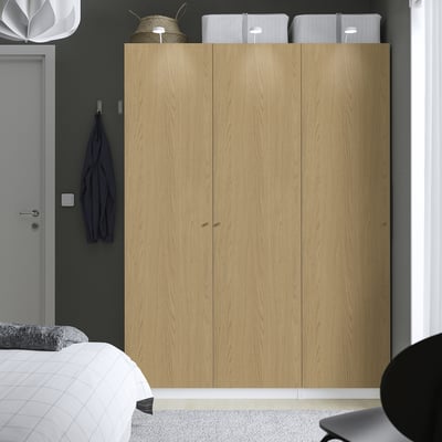 Modern bedroom with tall PAX wardrobe, clean design, bed, door, light.