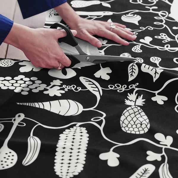 Cutting black-white patterned PIPDÅN fabric for sewing projects.