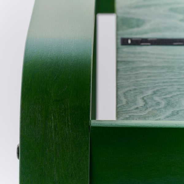 Green poang chair detail, smooth surface, visible grain texture.