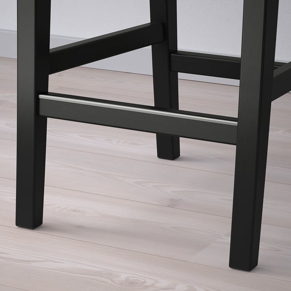 Black bar stool with wooden floor. Sturdy, modern design, metal details.