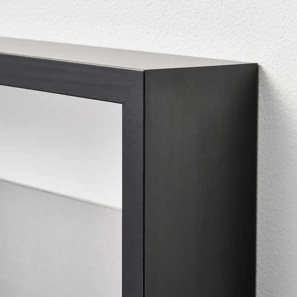 Close-up of a sleek, black SANNAHED picture frame corner against a white wall, showcasing its smooth, modern design.
