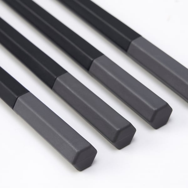 Six sleek, black chopsticks arranged diagonally, showcasing their smooth, hexagonal design and high-quality finish.