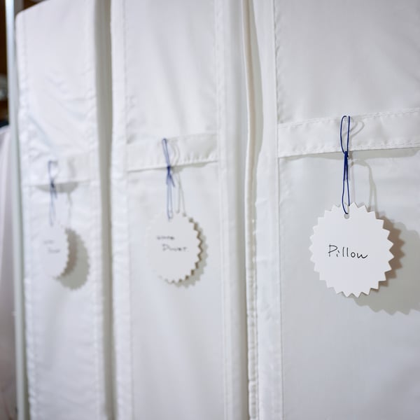 Blue-string storage bags in wardrobe, labelled pillow, duvet.