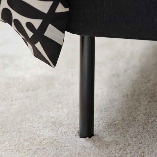 Modern bed with grey upholstery, padded headboard, black metal legs on light carpet.