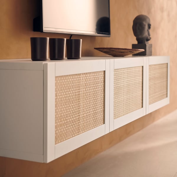 White woven sideboard with dark vases and wooden decor.