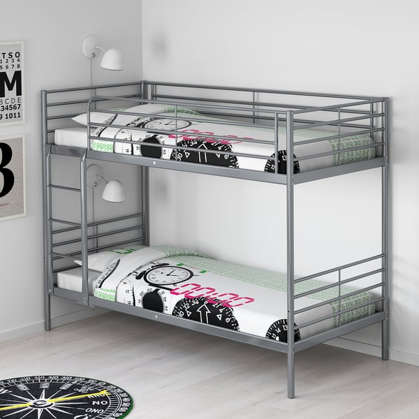 Silver SVÄRTA bunk bed with clocks design, fitting snugly into room corner, smaller than surrounding decor.