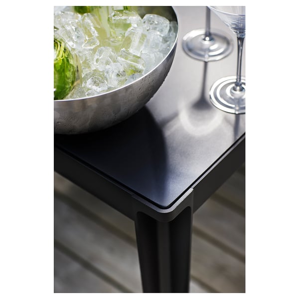 Small outdoor table with a large bowl of ice and bottles. Metal legs, sleek design. Perfect for patio use.