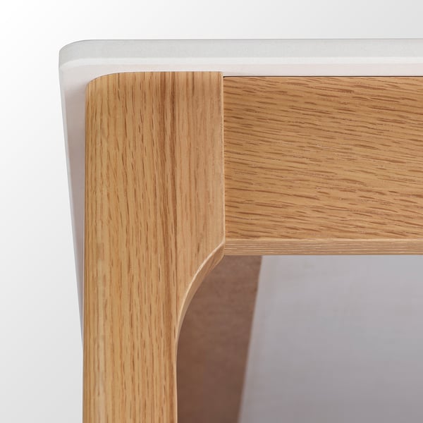 Close-up of TRÖDEN tables corner: sleek ceramic top, oak legs, quality finish.