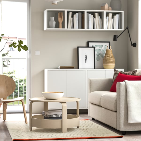 Neutral-colored area rug with diamond patterns, placed in a living room with a grey sofa, coffee table, and wooden chair.