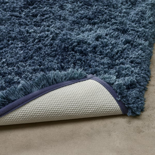 Puhasta modra kopalna preproga z belim robom, debela in mehka za toploto in udobje, vpojna in hitro sušeča, ostane na mestu z lateksno podlago.