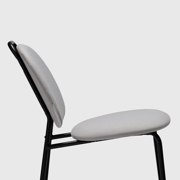 Sodoben stol s svetlo sivim sedežem in naslonom, črne kovinske noge, udoben kot.