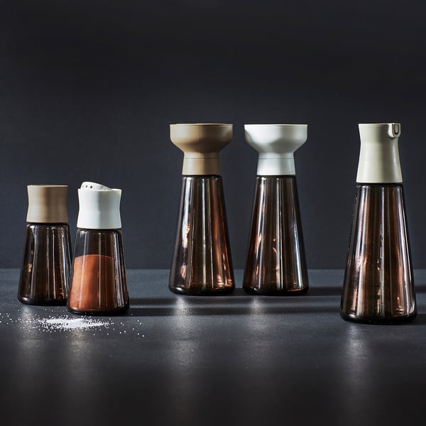 Pet kozarcev začimb, trije visoki, dva majhna rjava steklena stekla z lesenimi/belimi pokrovčki, razstavljenih kiparsko.