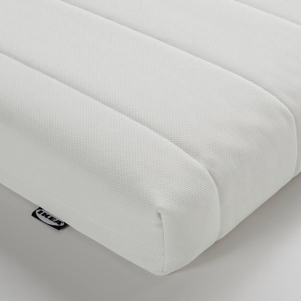 Bližnji posnetek bele penaste vzmetnice, ki prikazuje njeno teksturo in kakovost.