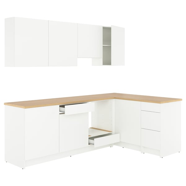 Sodoben beli kuhinjski set v obliki črke l s hrastovim pultom, dovolj prostora za shranjevanje in čistim dizajnom.