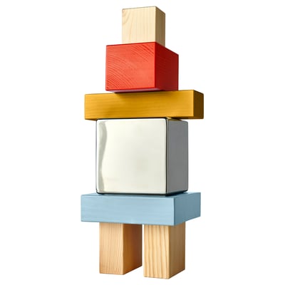 KONSTRUNDA: nerjaveče jeklo, borovi bloki v rdeči, zlati, modri, zloženi v barvit, geometrijski stolp.