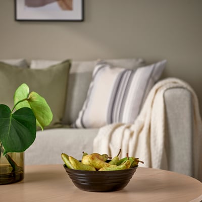 Vrtljiva steklena skleda, NÄTBARB, na mizi blizu zelene rastline, sivi kavč s črtastimi blazinami.