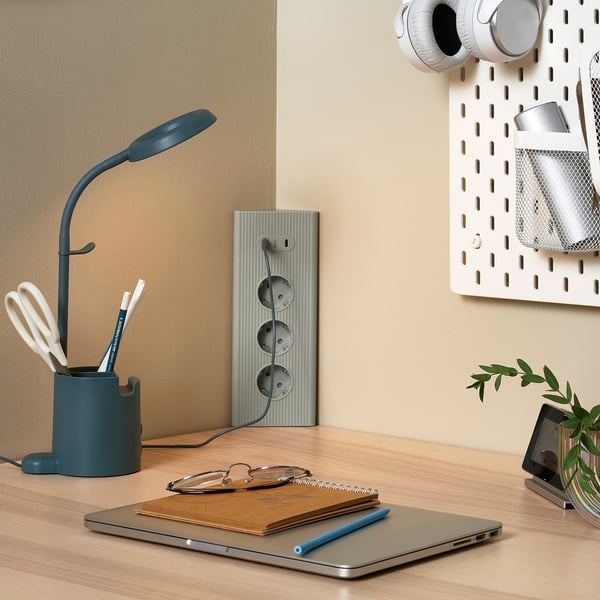 Urejena postavitev mize z modrim kablom SKOTAT, prenosnim računalnikom, prenosnim računalnikom in rastlino.