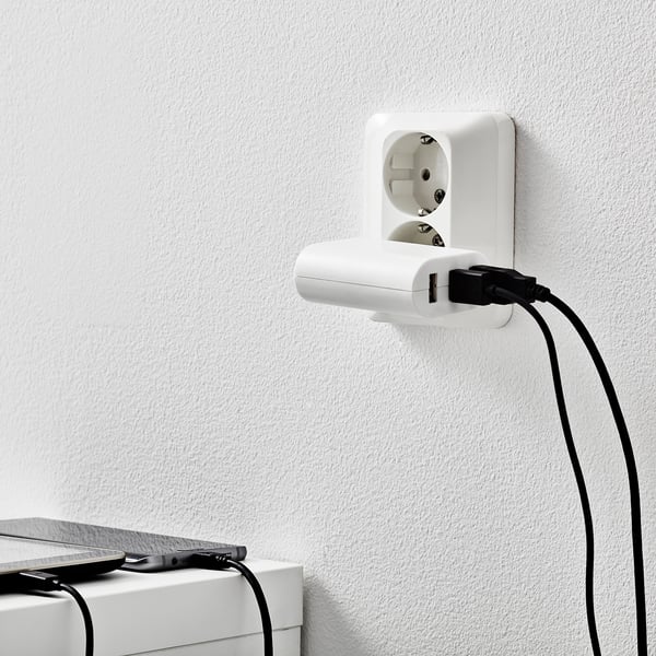 Stenski polnilnik s 3 USB vrati za napajanje naprav, ki prikazujejo njegovo funkcionalnost polnjenja.