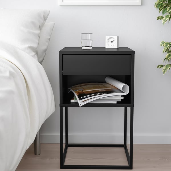 Majhna črna nočna omarica VIKHAMMER s predalom, polico in knjigami.