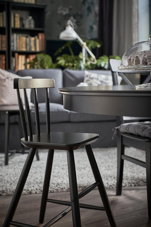 Black junior chair for kids at dining table, modern design, made of acrylic painted wood, supportive back and legs.