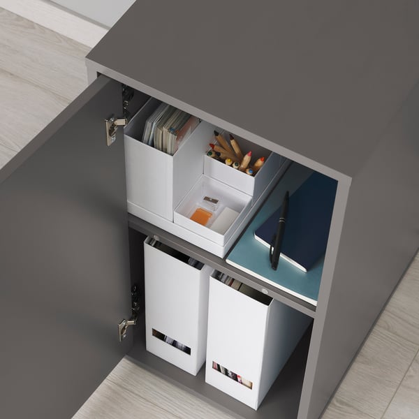 ALEX desk drawer open showing storage boxes with office supplies, including files, pencils, and a pen.