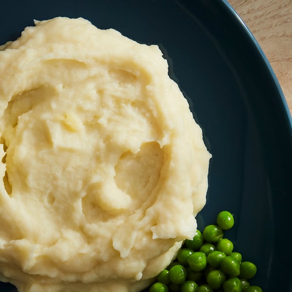 Blue plate with creamy yellow mash and green peas.